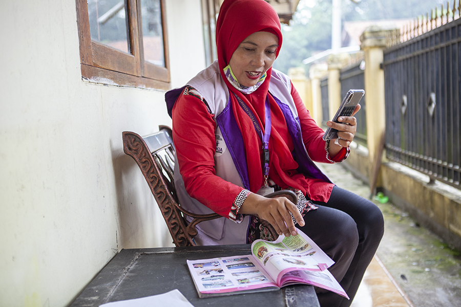 Erwati, a cadre for Gerai KIA Mobile is guiding a pregnant woman in using MCH Booklet (Photo by Oscar Siagian for USAID Jalin).jpg